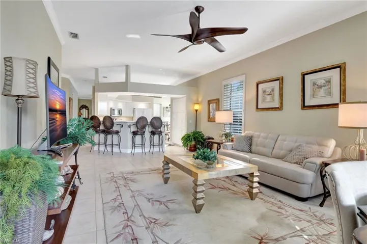 Living room featuring ceiling fan, crown molding, and light tile patterned flooring
