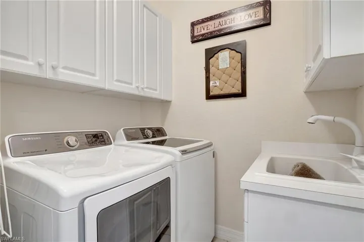 Washroom featuring cabinets, sink, and washing machine and clothes dryer