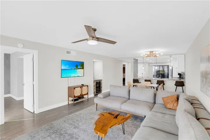 Living area featuring wood finish floors, a chandelier, ceiling fan, and beverage cooler