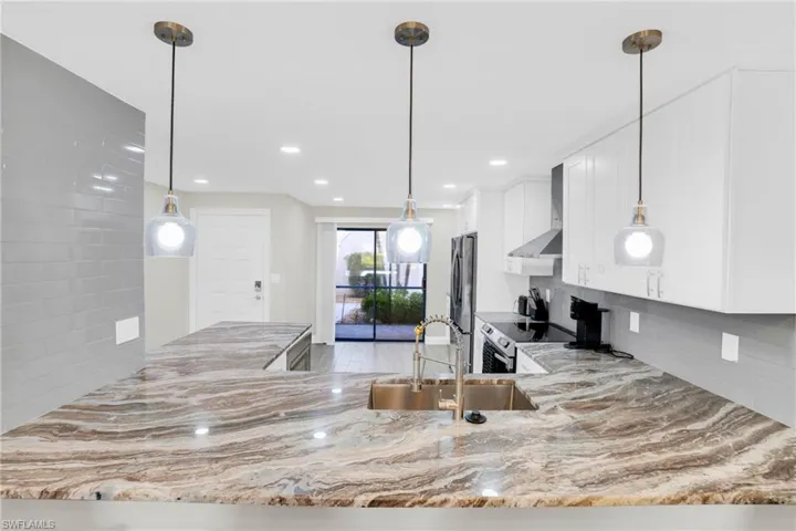Kitchen with pendant lighting, a peninsula, decorative backsplash, white cabinets, and recessed lighting