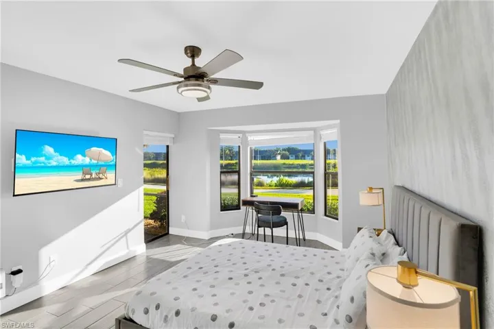 Bedroom featuring a water view, access to exterior, wood tiled floors, and a ceiling fan