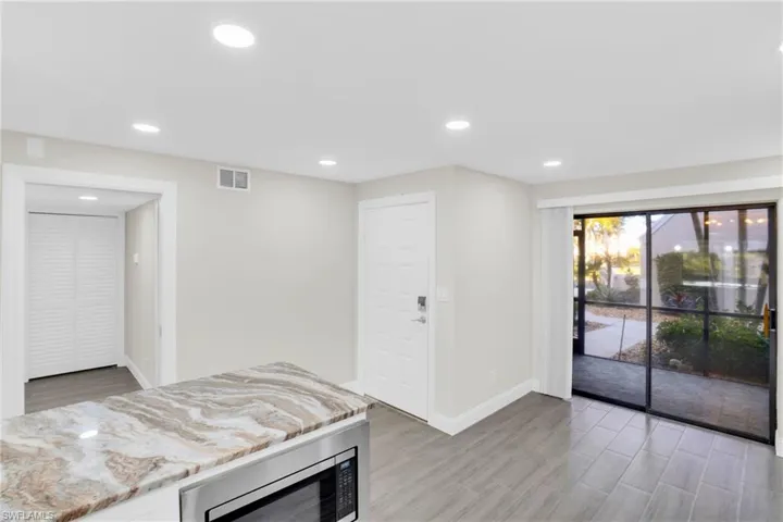Kitchen featuring light stone counters, stainless steel microwave, recessed lighting, and wood tiled floors