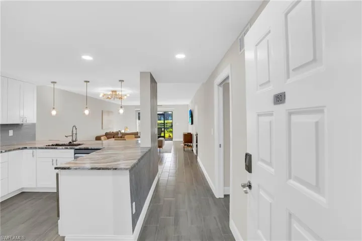 Kitchen with white cabinetry, light stone countertops, tasteful backsplash, a peninsula, and open floor plan
