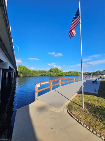 Waterfront walkway featuring a wood-rail perimeter, concrete paving, and direct water access