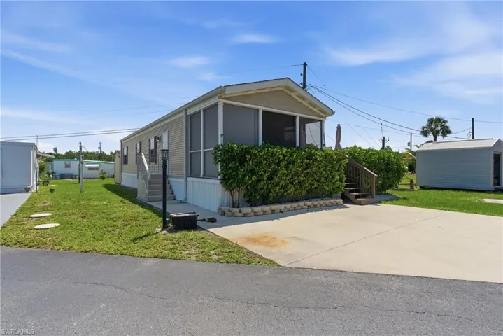Exterior featuring a screened porch, mature privacy landscaping, concrete driveway, and a detached storage shed