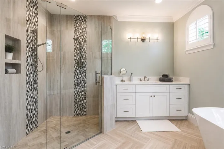 Glass-enclosed shower with decorative tile accents, a built-in niche, and dual shower heads