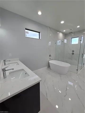 Bathroom featuring independent shower and bath and dual bowl vanity