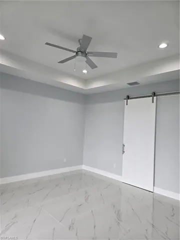 Tiled spare room with a barn door and ceiling fan