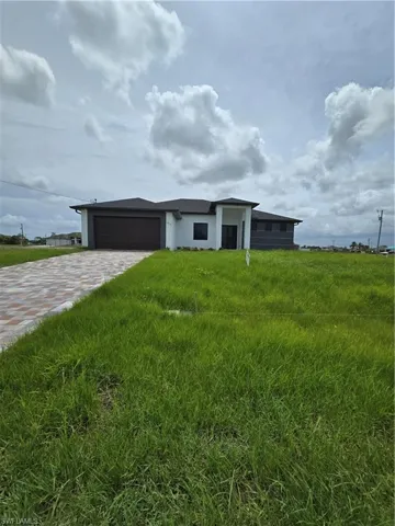 View of front of home with a garage and a front lawn