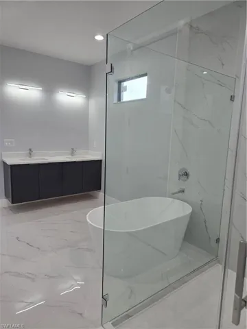 Bathroom with tile flooring, separate shower and tub, and vanity