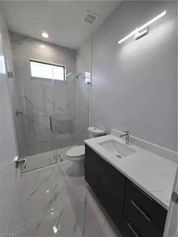 Bathroom featuring walk in shower, vanity, toilet, and tile floors
