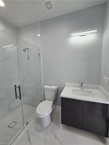 Bathroom with a shower with shower door, vanity, toilet, and tile floors