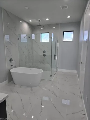 Bathroom featuring tile flooring, vanity, tile walls, and plus walk in shower