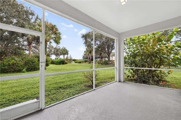 Screened lanai with a textured concrete floor, overhead lighting fixture, and extensive landscaping
