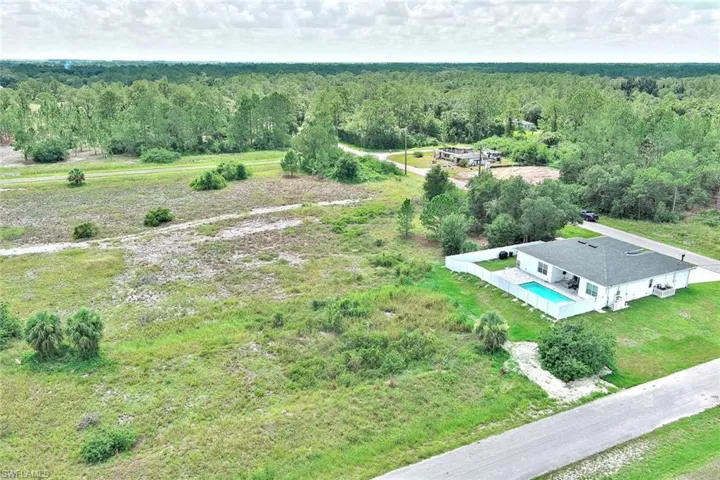 Aerial view of property and surrounding area with a pool and a forest