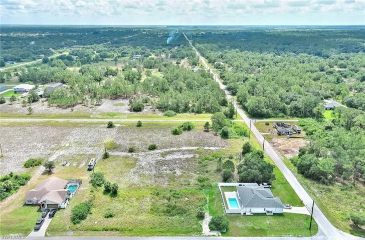 Drone / aerial view of a heavily wooded area and a pool area