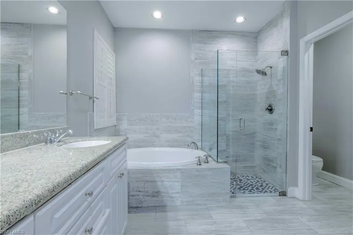 Bathroom featuring a garden tub, toilet, recessed lighting, vanity, and a shower stall