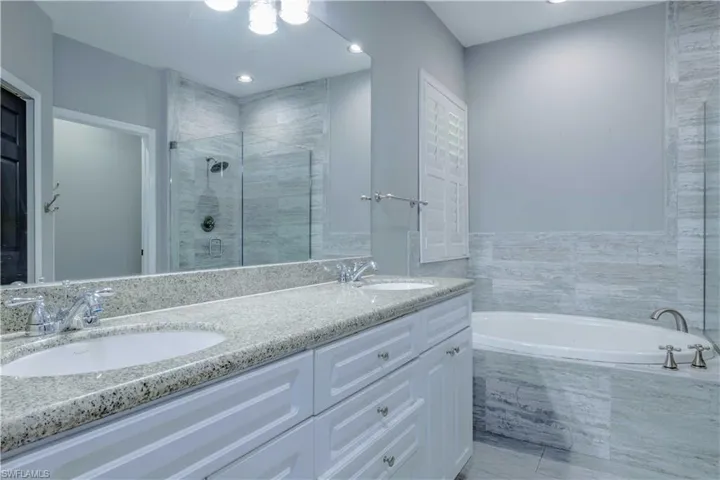 Full bath with double vanity, a stall shower, a sink, and a bath