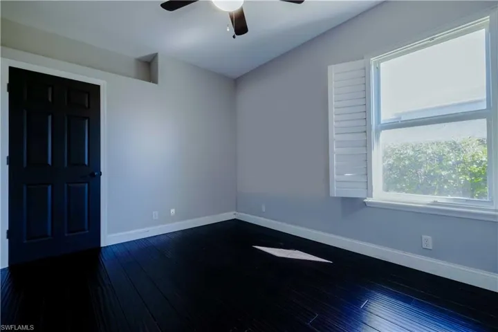 Unfurnished room featuring dark wood-style floors, ceiling fan, and baseboards