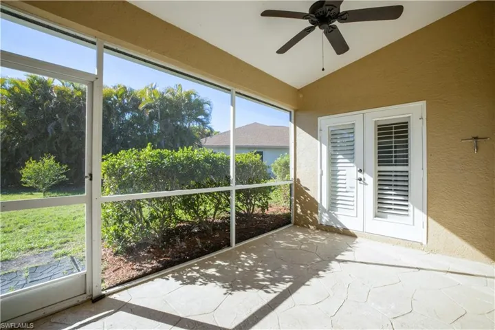 Unfurnished sunroom featuring lofted ceiling, a ceiling fan, and french doors