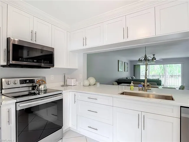 Modern kitchen featuring white shaker cabinetry, stainless steel appliances, a stainless steel sink with a gooseneck faucet, and light-toned countertops