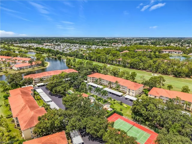 Expansive community featuring multiple buildings with tile roofs, a tennis court, swimming pool, and covered parking