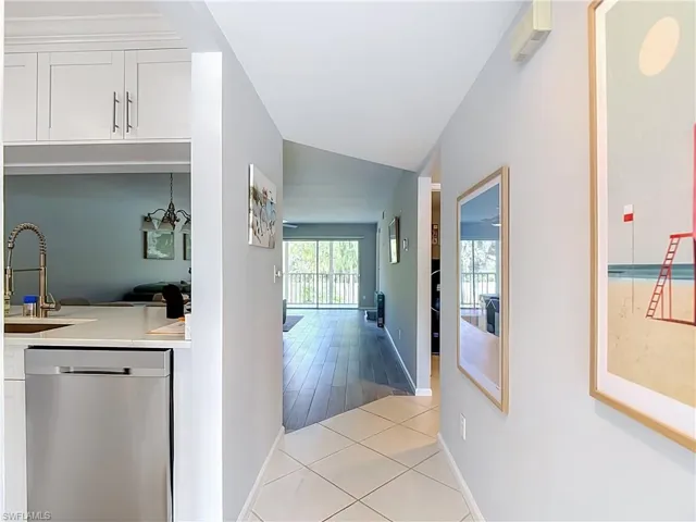 Kitchen featuring stainless steel appliances, white cabinetry with crown molding, white tile flooring, a built-in pantry, and a window with pleated blinds