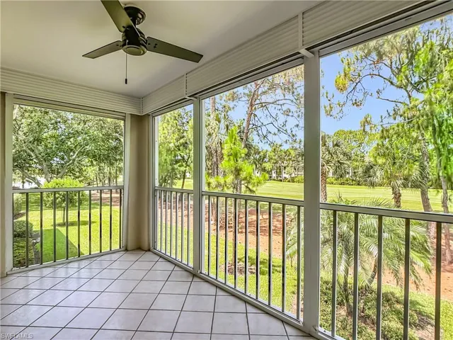 Screened porch featuring tiled flooring, a ceiling fan, and expansive outdoor scenery with mature trees and green areas