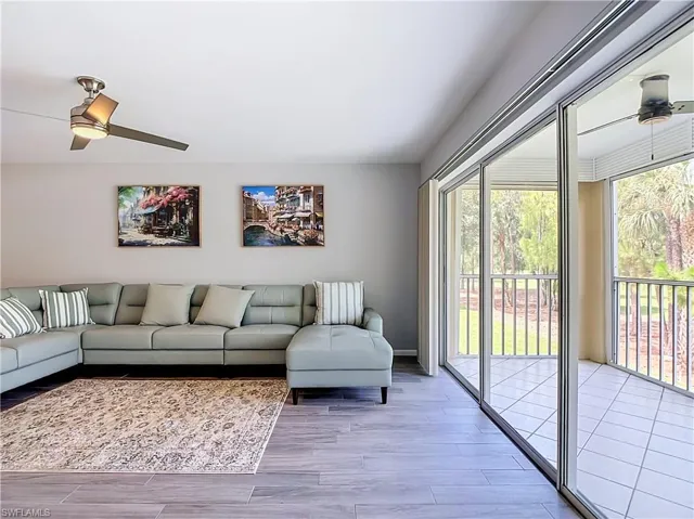 Living space featuring wood-finish flooring, a contemporary ceiling fan, and sliding glass doors opening to an enclosed balcony