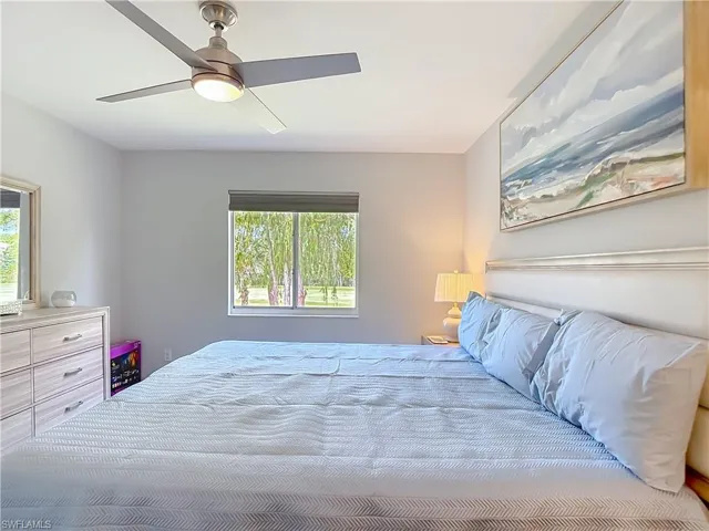 Bedroom featuring a ceiling fan with integrated lighting, a window with exterior views, and neutral wall tones