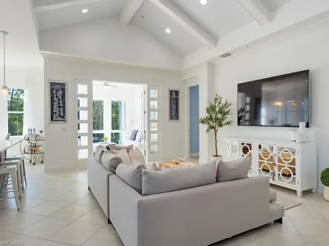 Living room featuring light tile patterned flooring, beamed ceiling, high vaulted ceiling, and recessed lighting