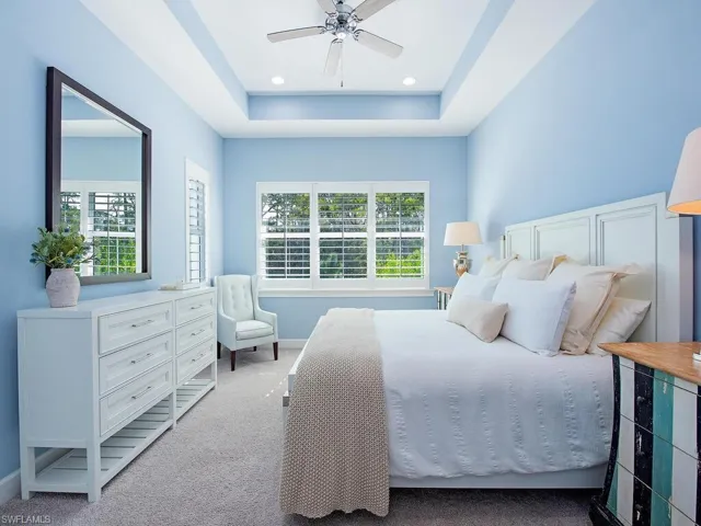 Carpeted bedroom featuring a tray ceiling, ceiling fan, and recessed lighting