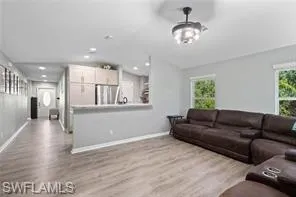 Living area with baseboards, lofted ceiling, and wood finished floors