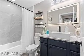 Full bathroom with vanity, shower / bath combo, and toilet