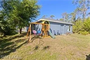 Rear view of house with a playground and a lawn