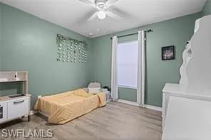 Bedroom featuring a ceiling fan, baseboards, and light wood-type flooring
