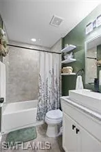Full bath featuring shower / bath combo with shower curtain, visible vents, toilet, and vanity