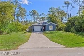View of front of house featuring concrete driveway, an attached garage, and a front yard