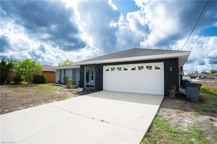 Ranch-style house with an attached garage, driveway, roof with shingles, and stucco siding