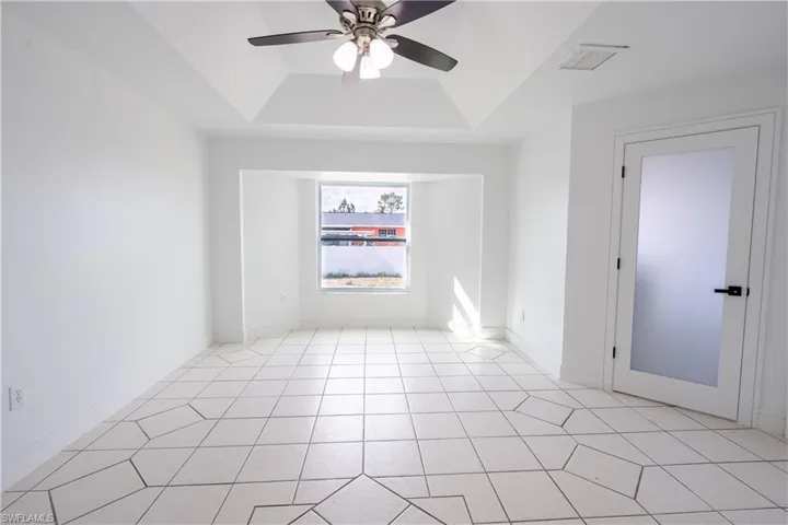bedroom with ceiling fan and a raised ceiling