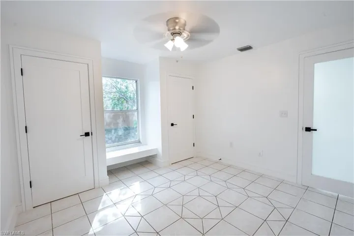 bedroom featuring light tile patterned floors, a ceiling fan, and two closets