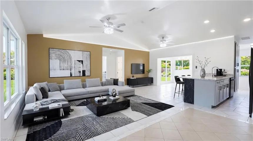 Staged - Living room featuring light tile patterned floors, vaulted ceiling, ceiling fan, and recessed lighting
