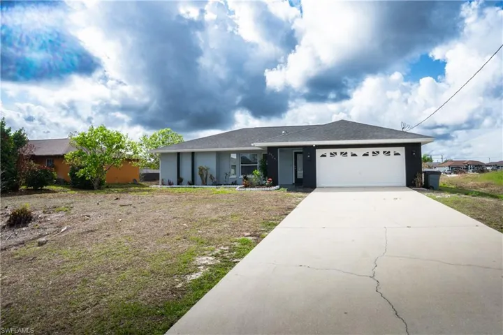 Ranch-style house with a garage, driveway, and stucco siding