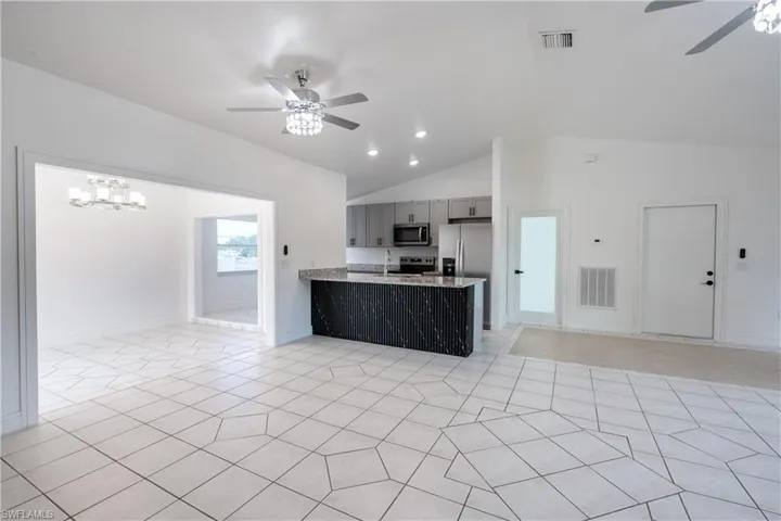 Kitchen featuring a ceiling fan, open floor plan, a peninsula, gray cabinets, and vaulted ceiling