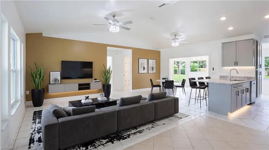 Staged - Living area with a ceiling fan, light tile patterned floors, lofted ceiling, and recessed lighting