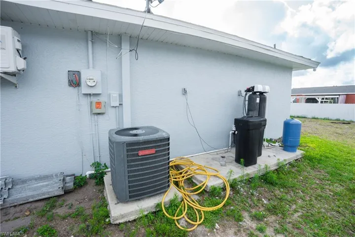 Exterior view of stucco siding, a water softener, and a water pressure tank