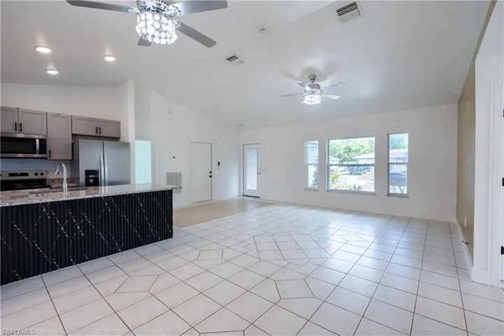 Kitchen with a ceiling fan, stainless steel appliances, gray cabinetry, light granite countertops, and light tile patterned flooring