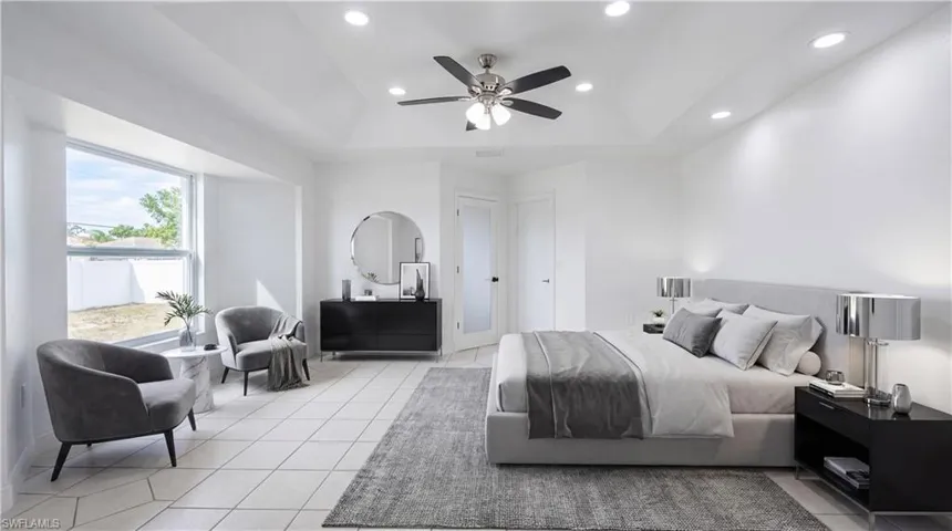 Staged - Bedroom featuring a raised ceiling, ceiling fan, recessed lighting, and light tile patterned floors
