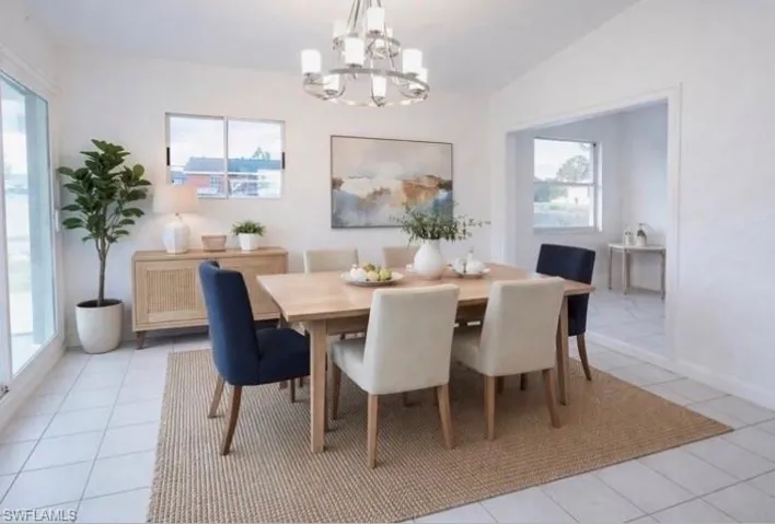 Staged - Dining space featuring a chandelier, light tile patterned floors, and lofted ceiling