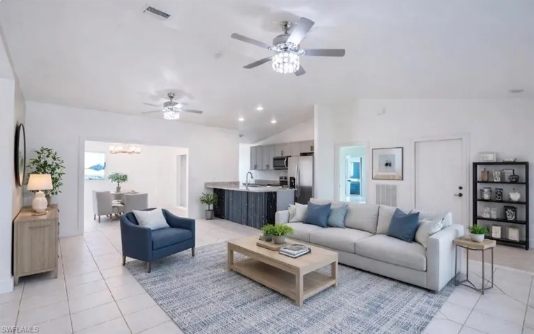 Staged - Living area featuring ceiling fan, vaulted ceiling, light tile patterned floors, and suspended lighting